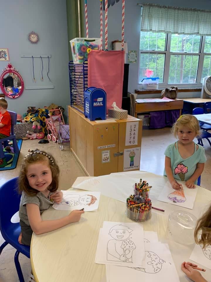 Two children coloring at a table in a classroom