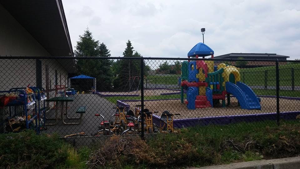 A fenced playground area with colorful equipment and sand