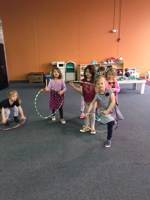 Children playing with hula hoops in a room