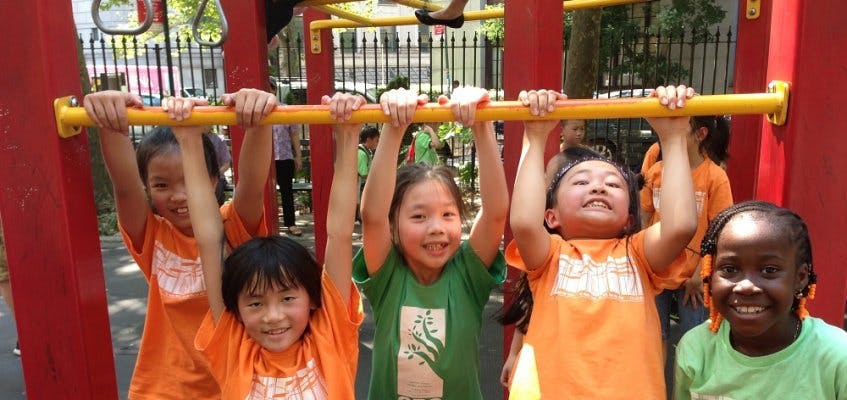 Children hanging from a yellow bar on a playground