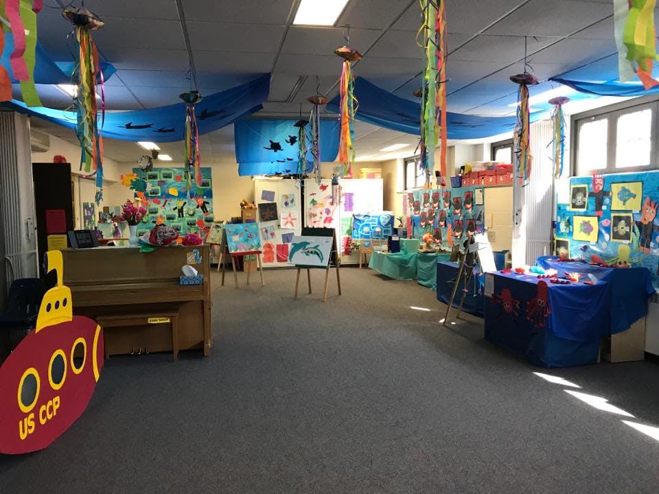 Room decorated with blue fabric on ceiling, colorful streamers, and artwork
