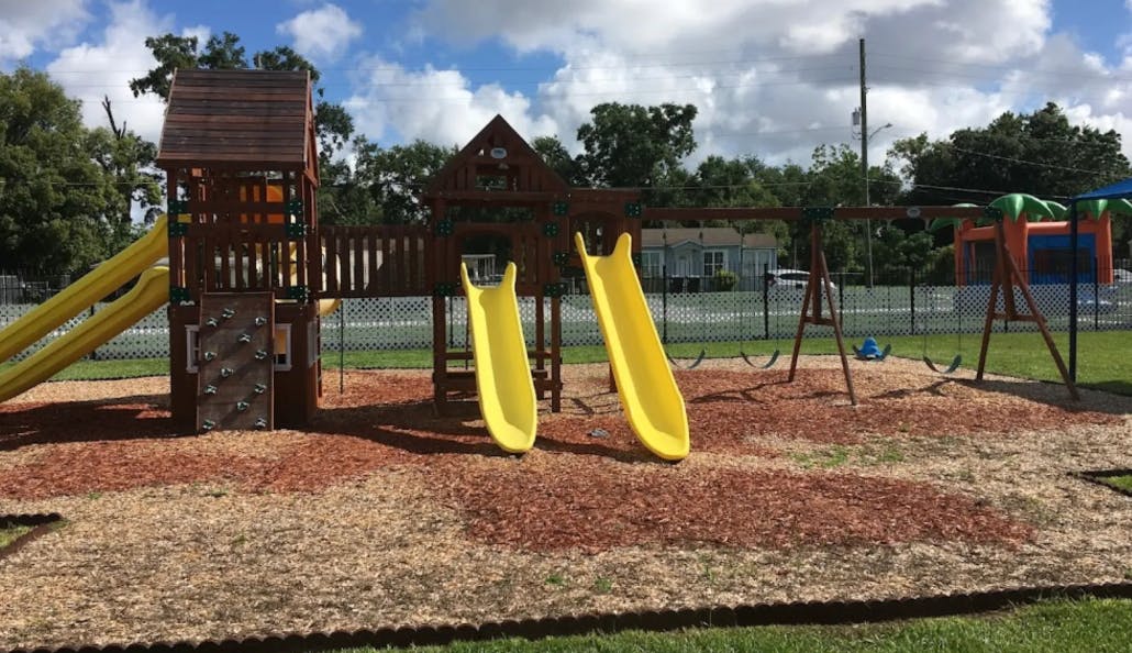 Playground with wooden structure, yellow slides, and swings