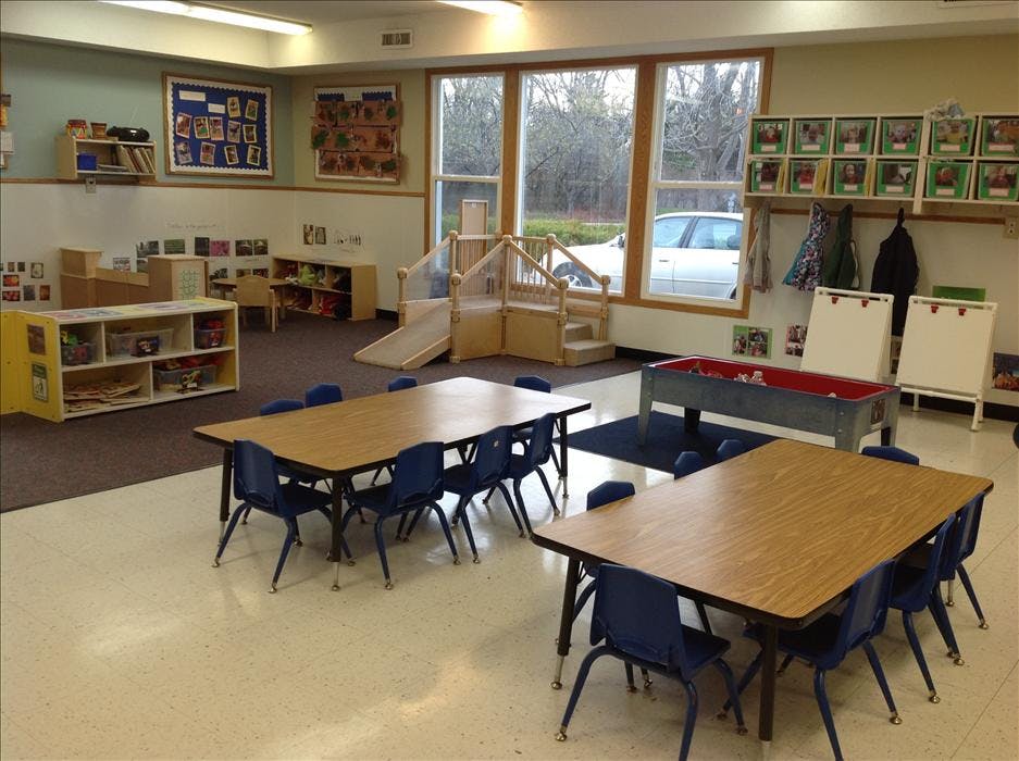 Classroom with tables, chairs, play area, and large windows