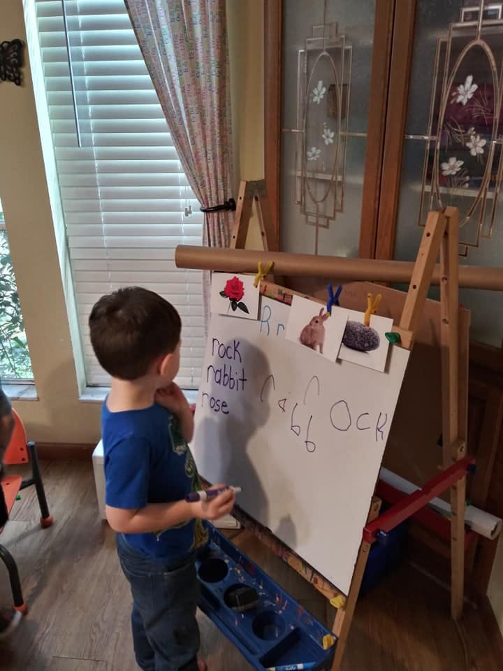 Child standing at an easel with words and pictures on a whiteboard