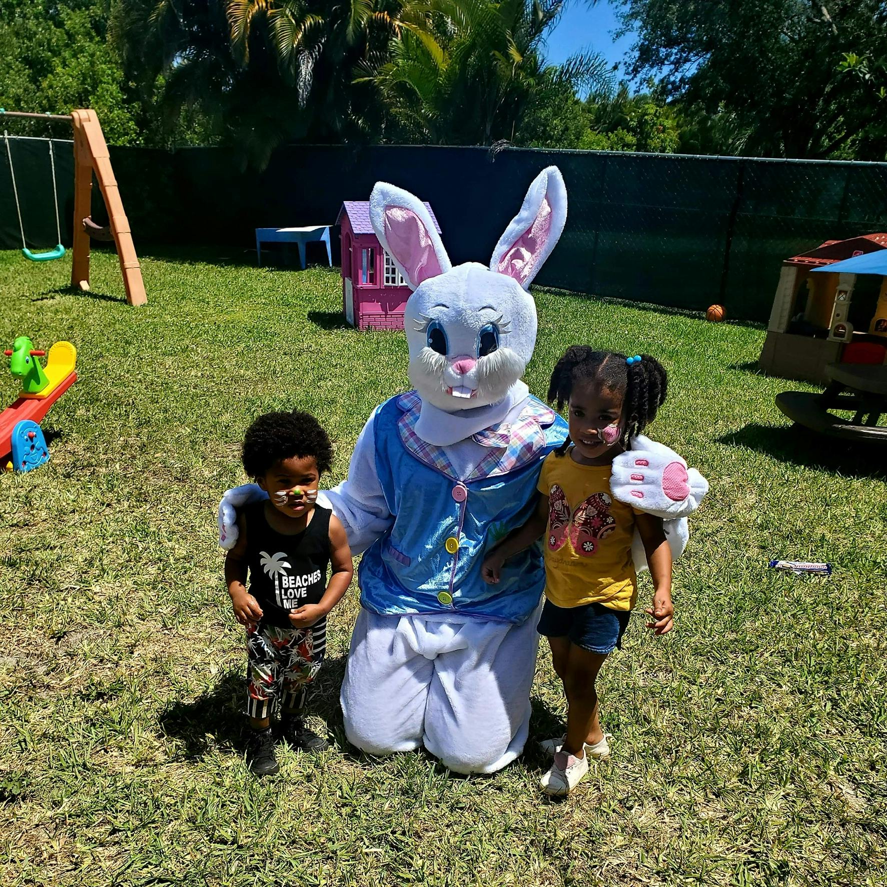 Easter bunny mascot kneeling with two children