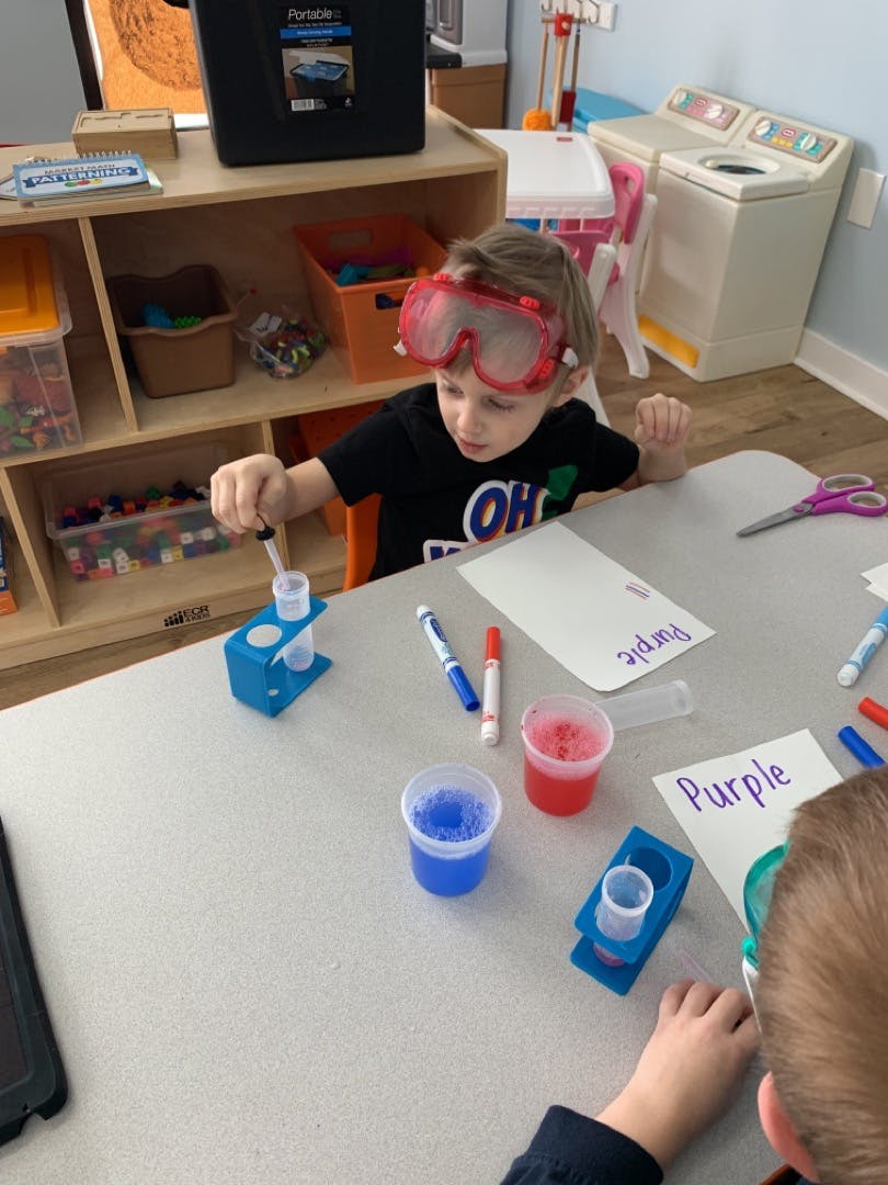 Child in goggles doing a science experiment with liquids