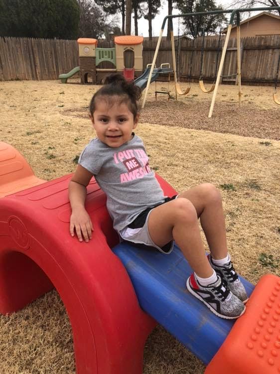 Child sitting on a small red and blue slide on a playground