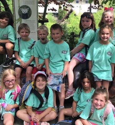 Group of children and teens in matching shirts sitting outdoors