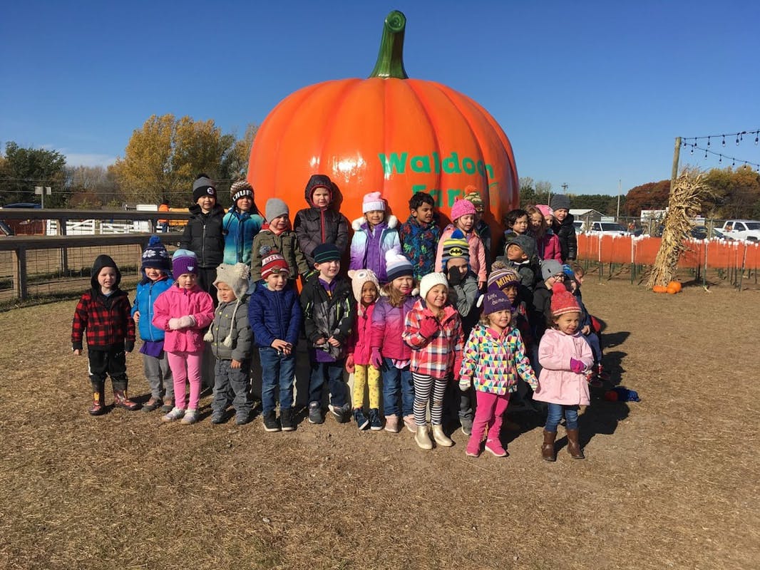 Group of children and adults standing in front of a large inflatable pumpkin