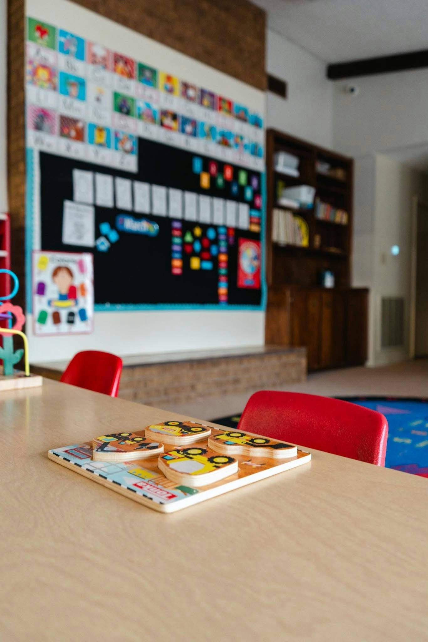 Wooden puzzle on a table with red chairs in a classroom