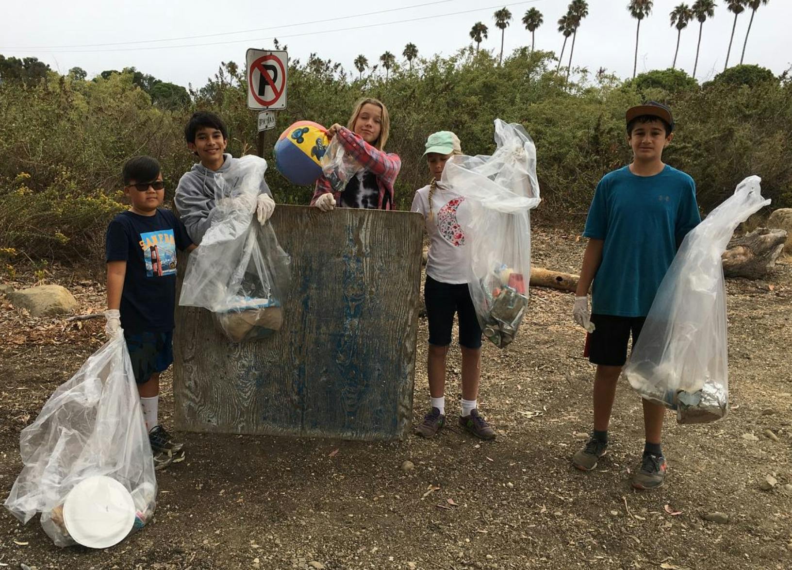 Group of people holding bags of collected trash