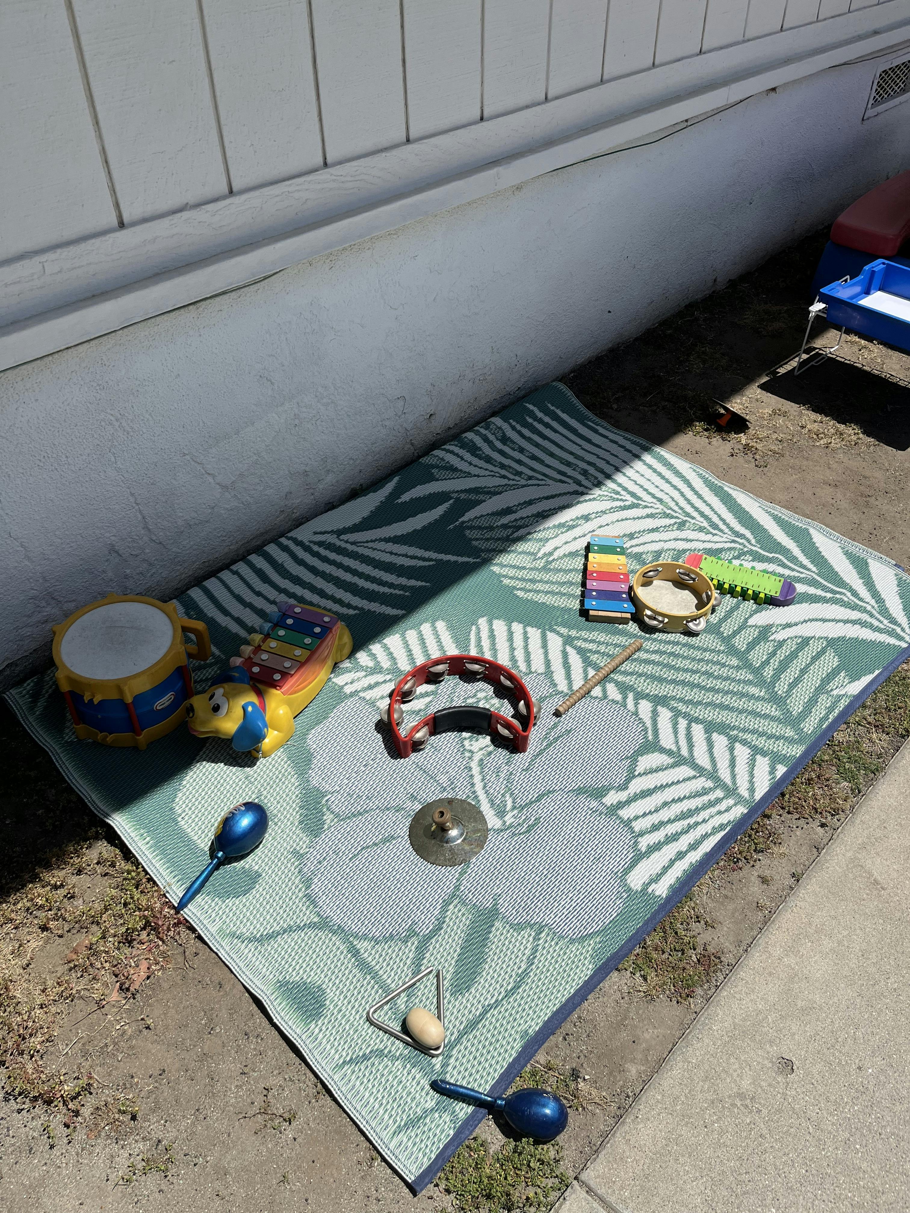 A collection of colorful musical toys on a patterned outdoor rug