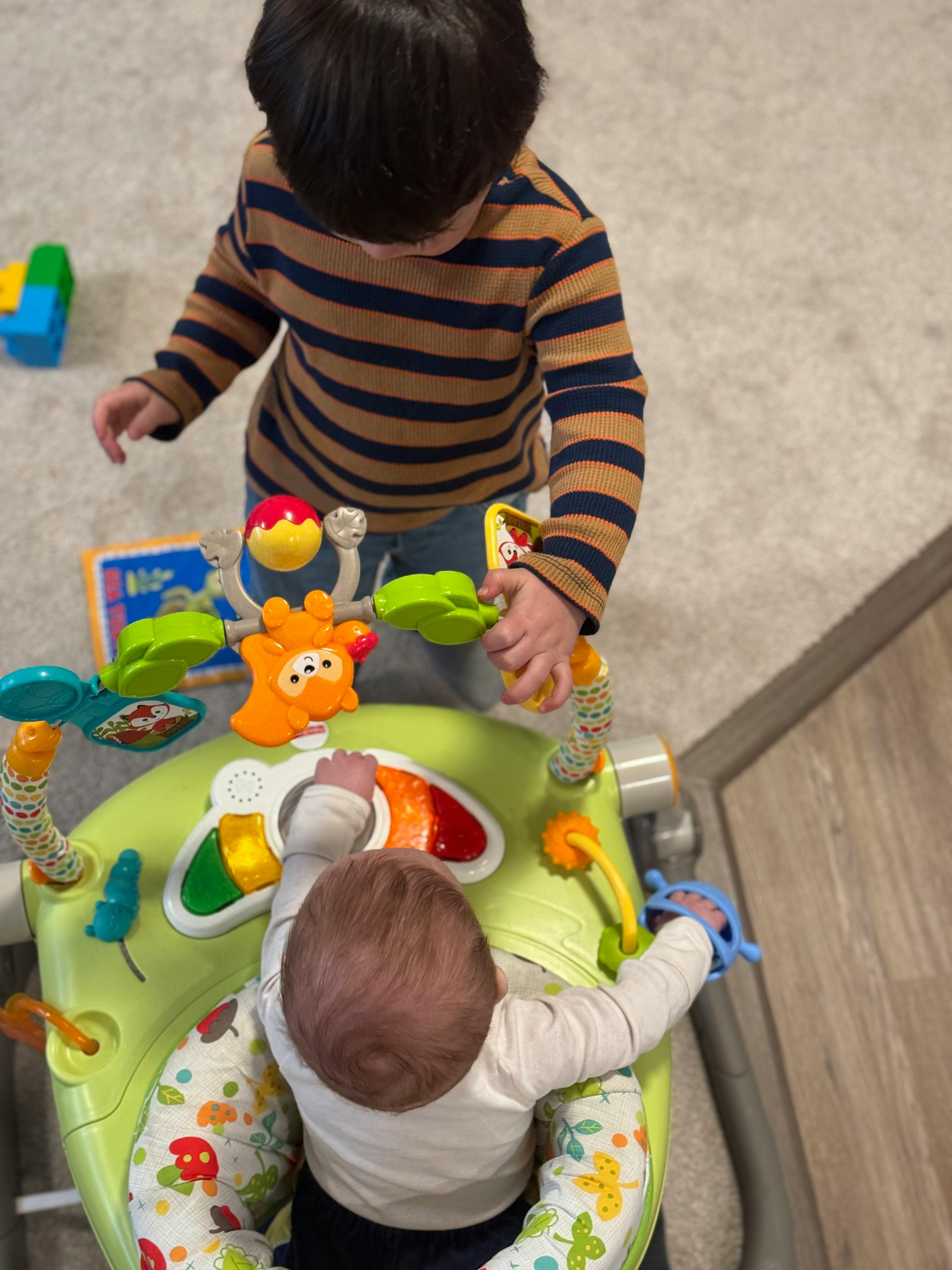 Child playing with baby in activity center