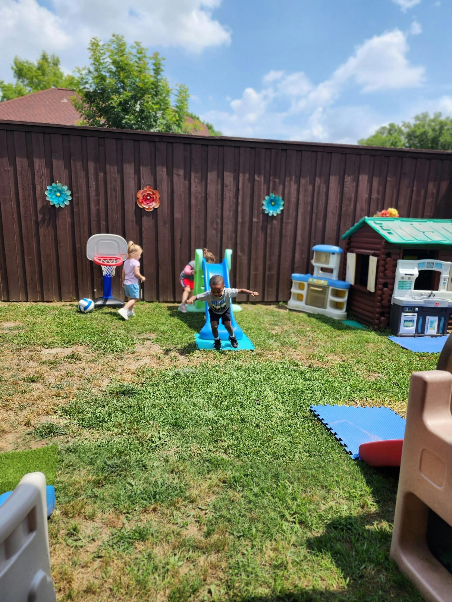 Children playing on a slide and with a basketball hoop in a backyard