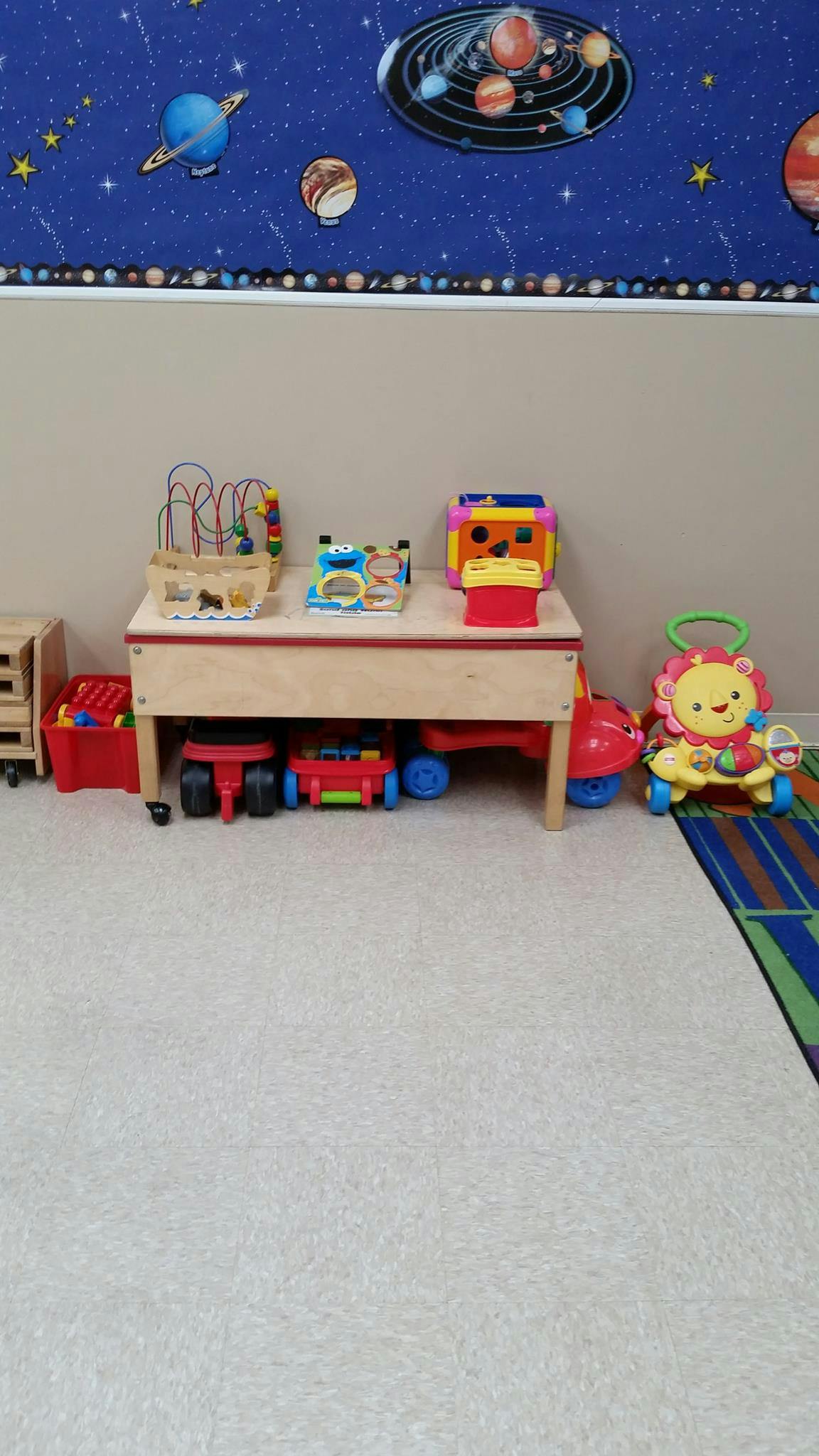 Children's play area with a table, toys, and a space-themed wall border