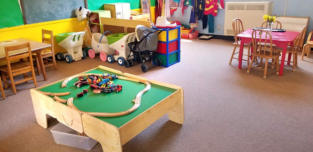 Playroom with a train table, small chairs, and toys