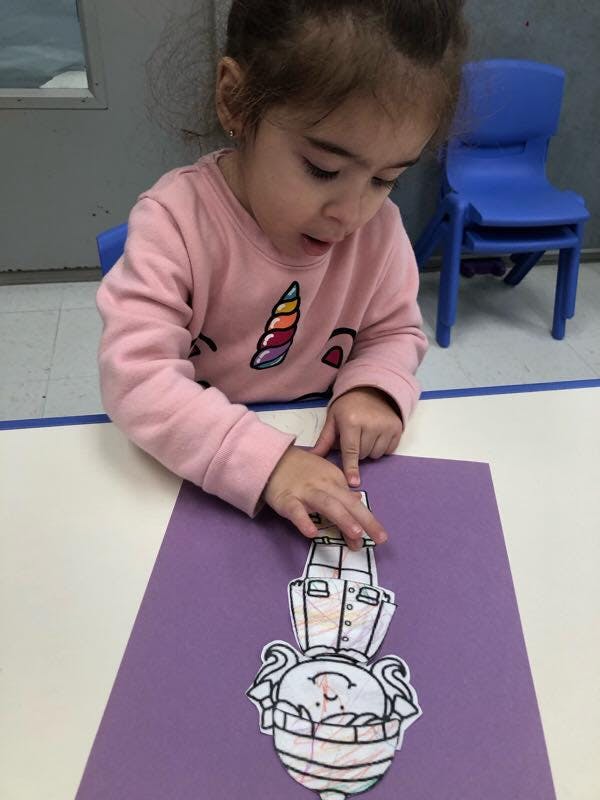 Child playing with a paper cutout on a purple sheet