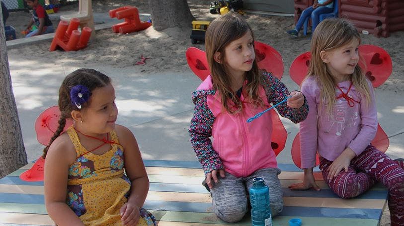 Three children with wings playing outdoors