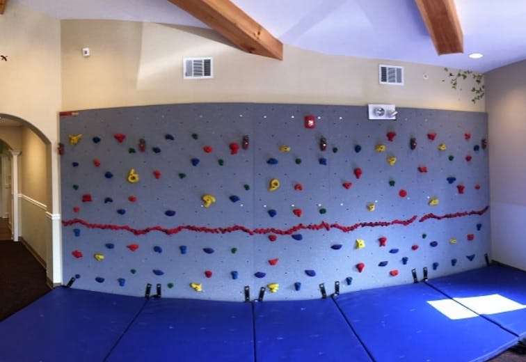 Indoor climbing wall with colorful holds and blue safety mats