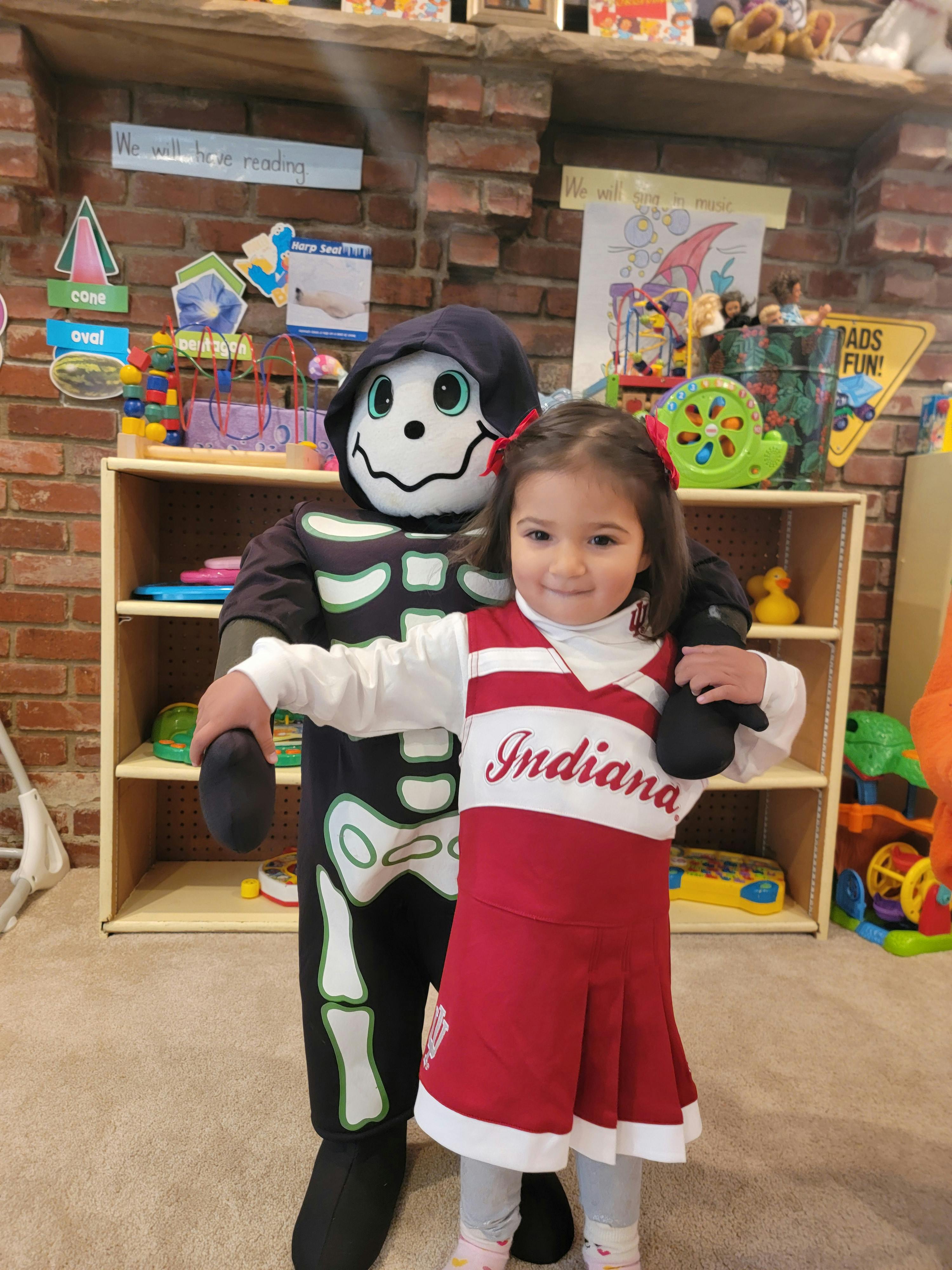Child in red and white dress with a person in a skeleton costume