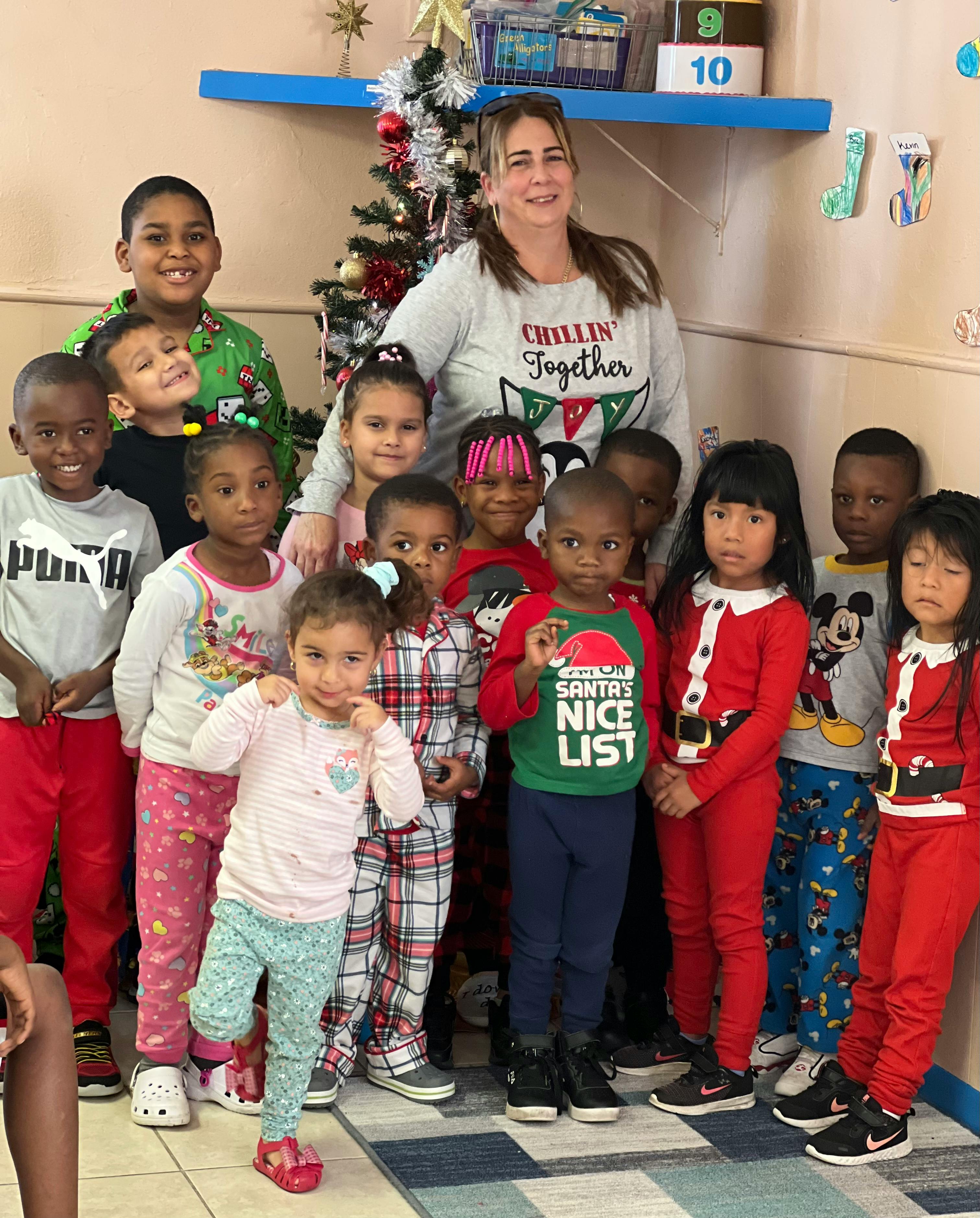 Adult and multiple children posing for a photo in a classroom