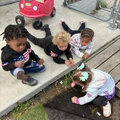 Four children playing on the ground outdoors