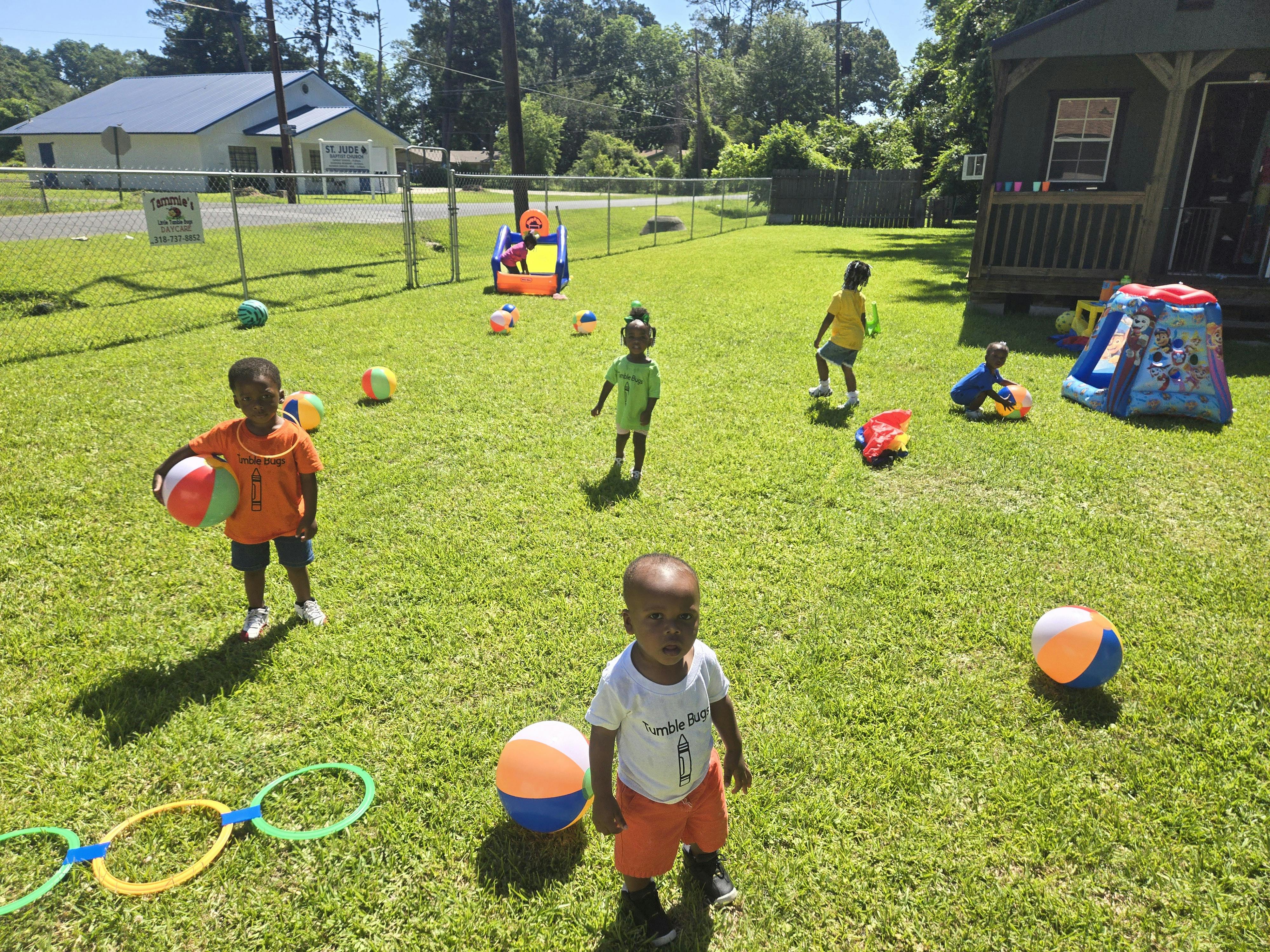 Children playing with balls and toys in a grassy yard