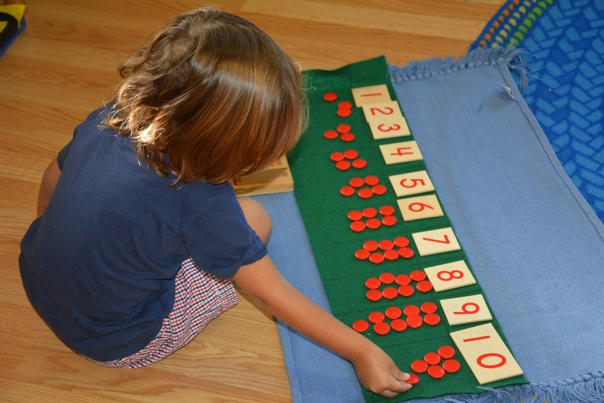 Child counting with number cards and red counters