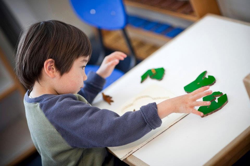 Child playing with green shapes on a white surface