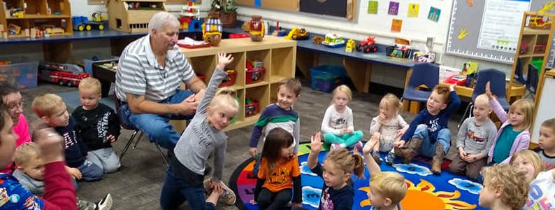 Adult and children sitting on a rug in a classroom