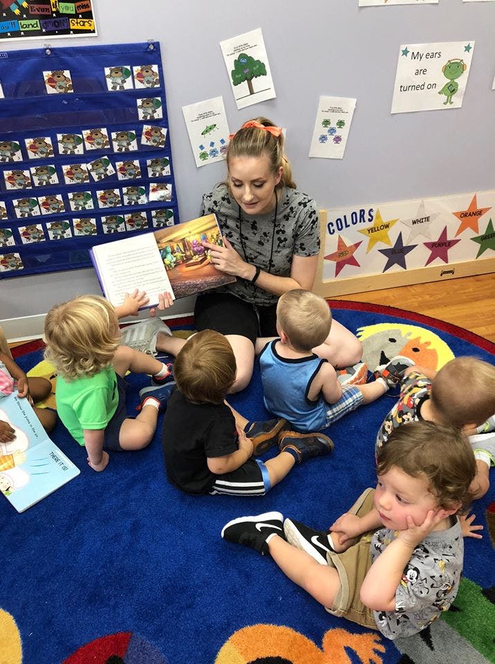 Person reading a book to several children in a classroom