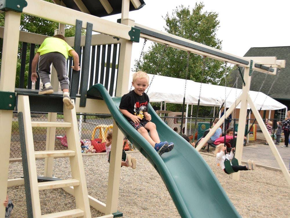 Child on a slide and another child climbing a ladder on a playground
