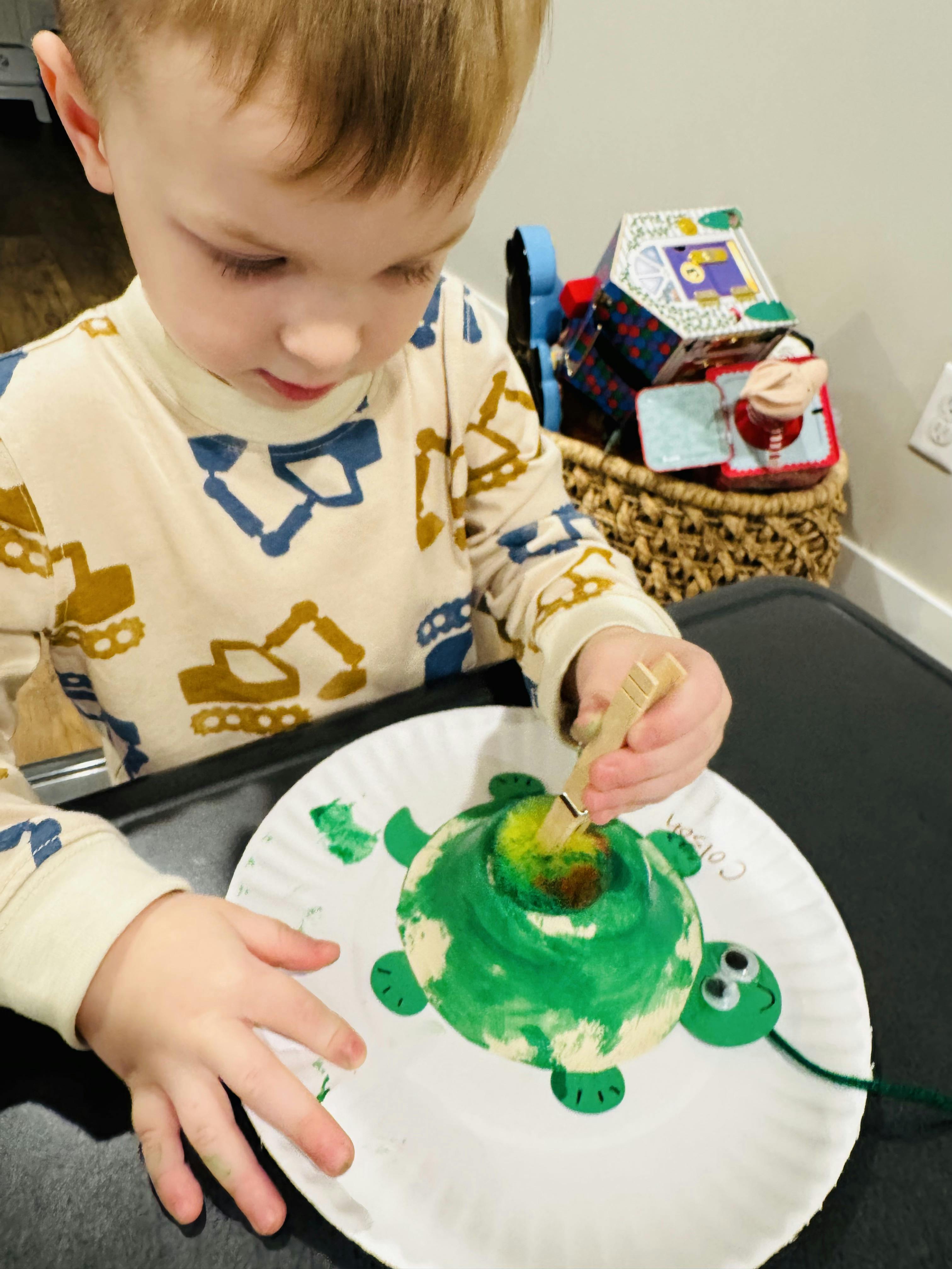 Child painting a paper plate turtle