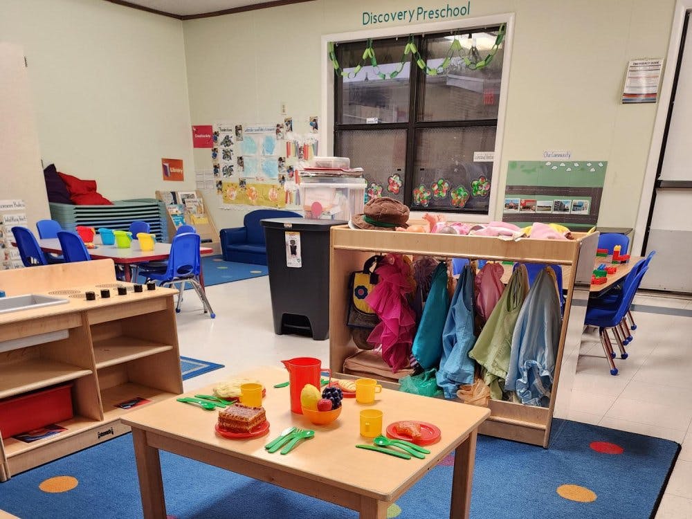 A preschool classroom with play kitchens, tables, and dress-up clothes