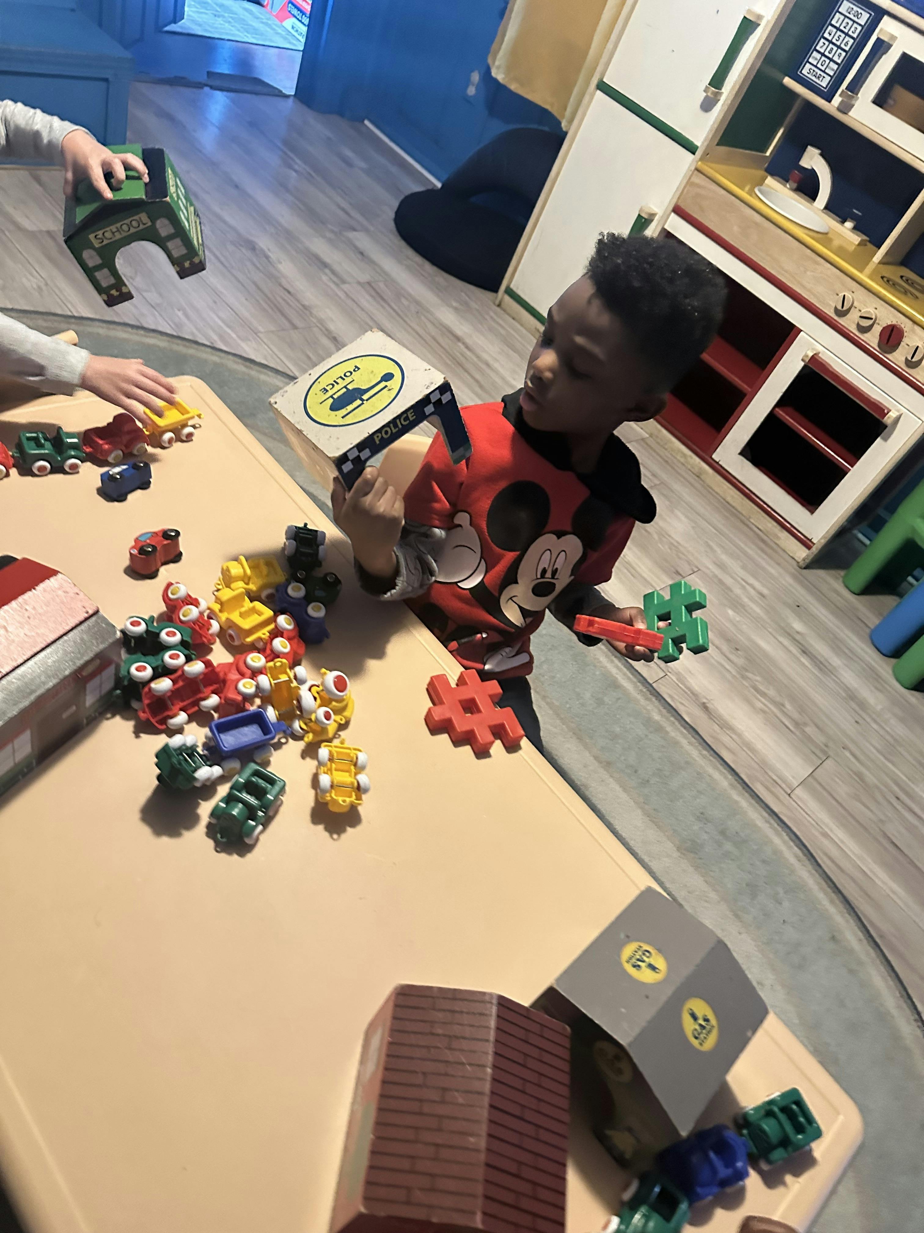 Child playing with toy vehicles and building blocks on a table