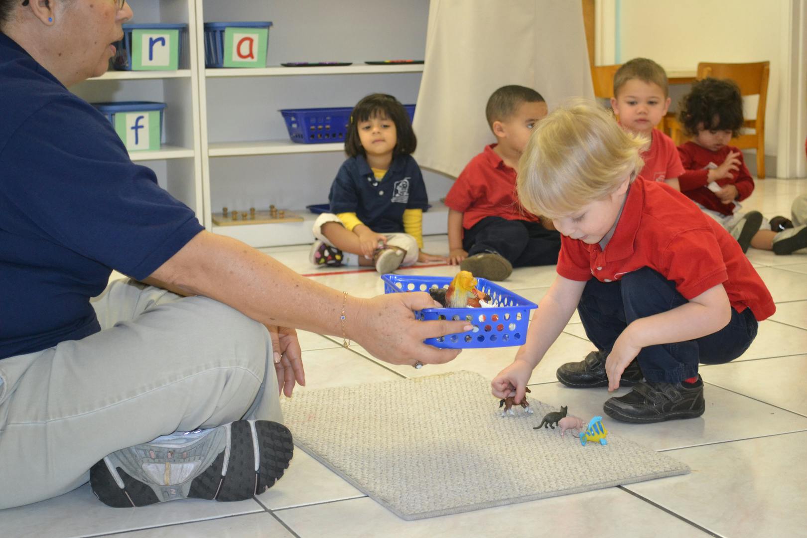 Person and child playing with small toys on the floor
