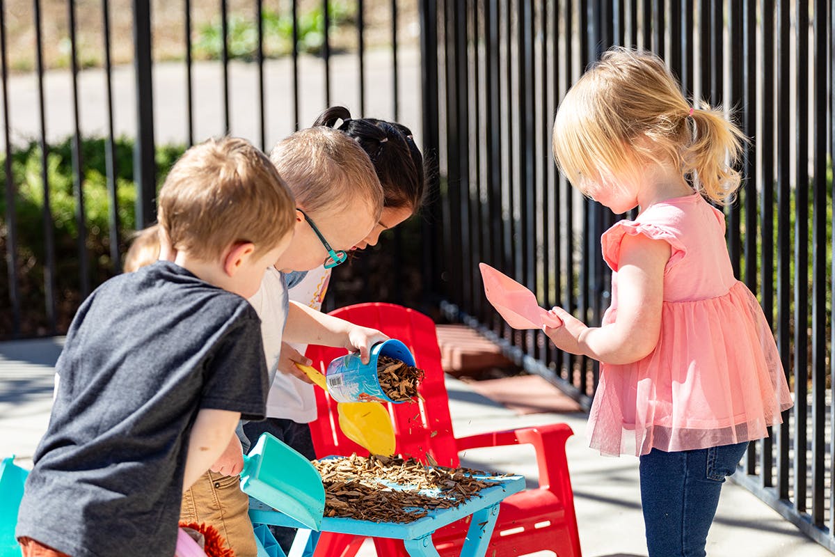 Children playing with wood chips and sand toys