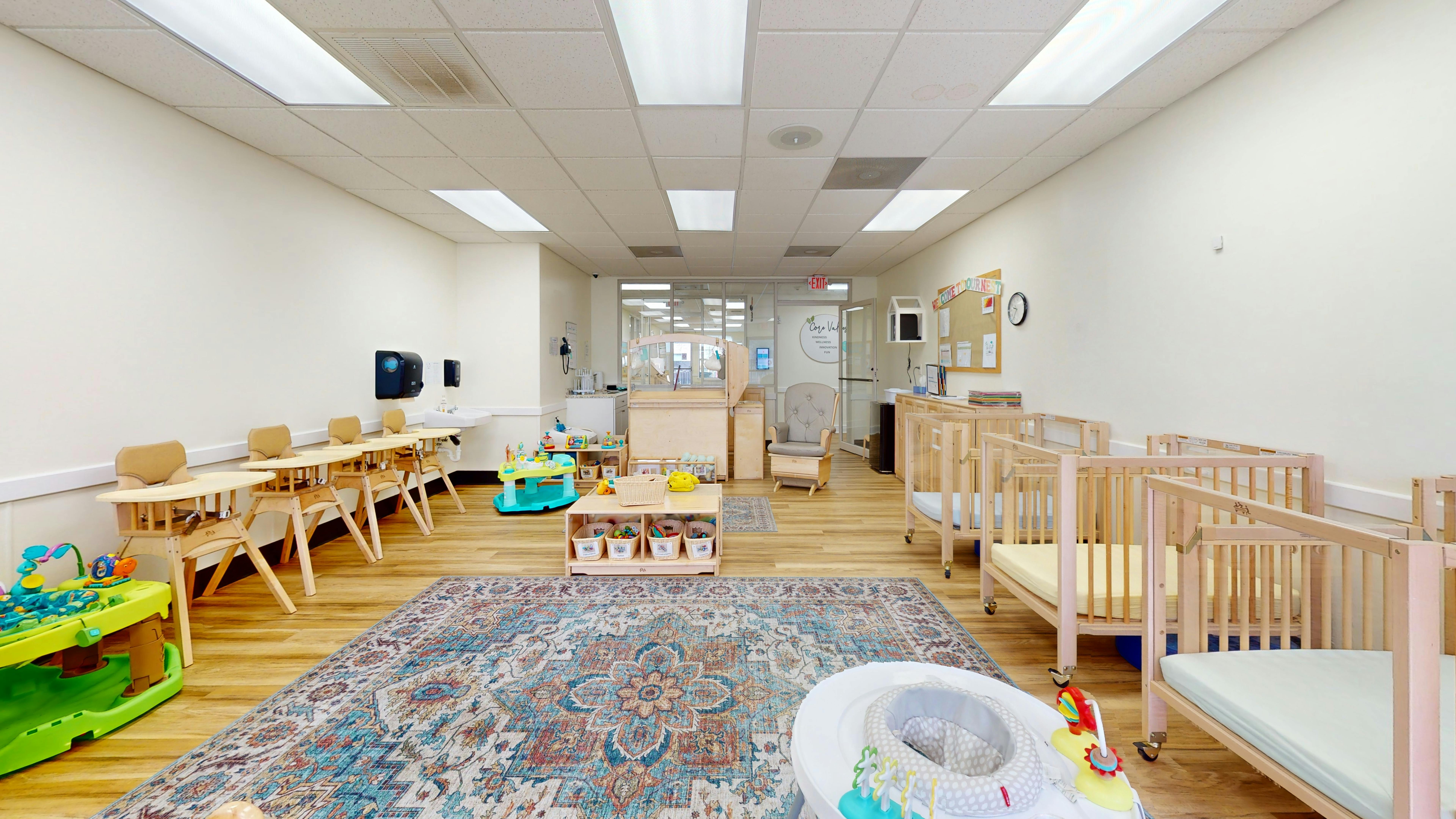 Room with small tables and chairs, cribs, and a rug