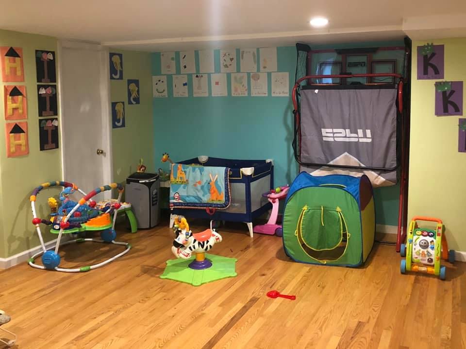 Playroom with a crib, playpen, and various toys on the floor toys