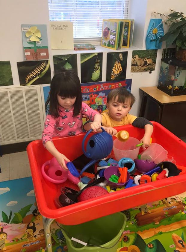 Two children playing with toys in a red bin