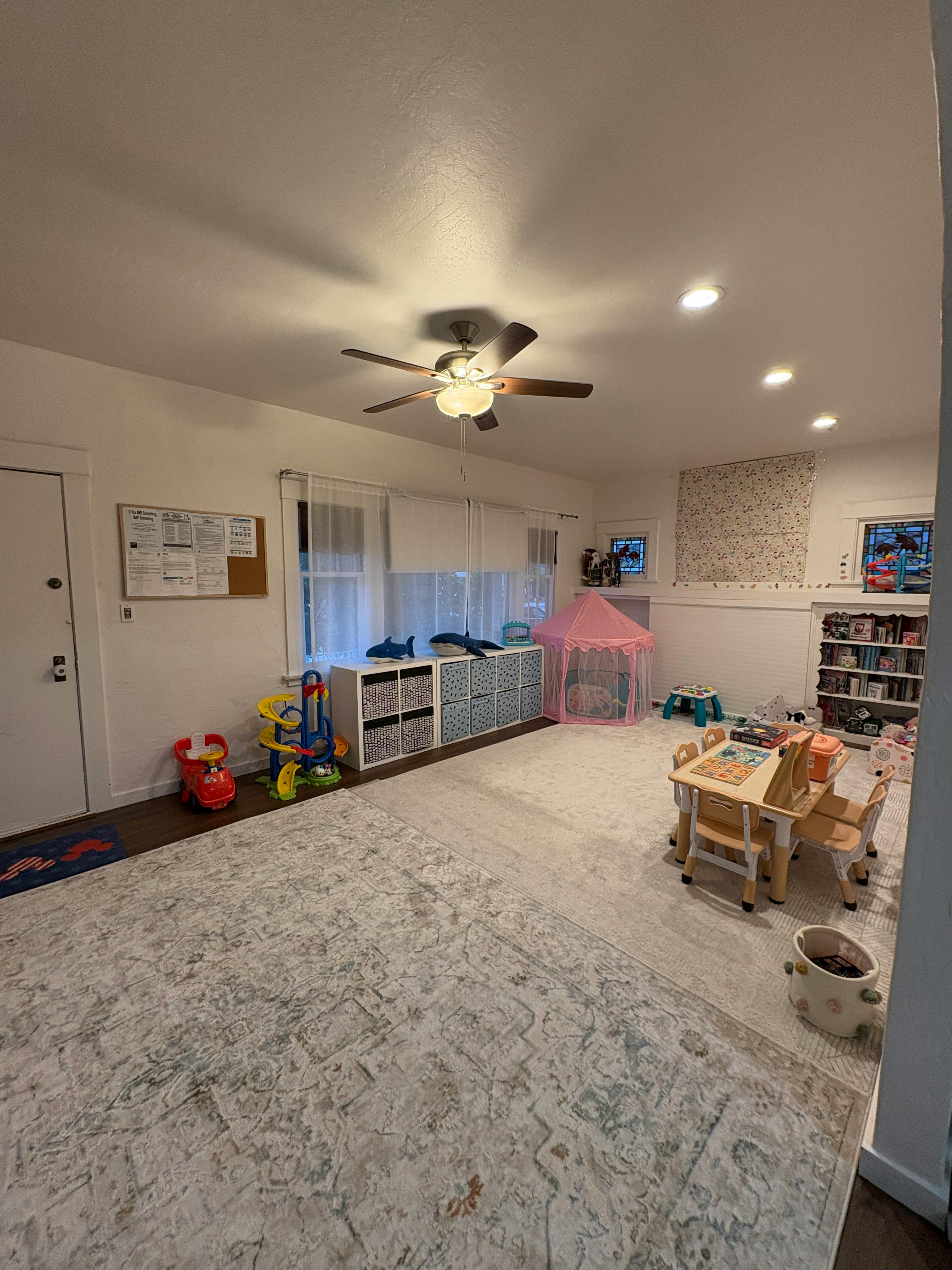 A playroom with a small table and chairs, toy storage, and a pink tent