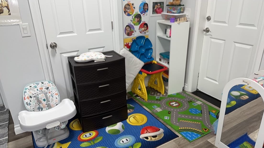Child's room with a high chair, dresser, and colorful rugs