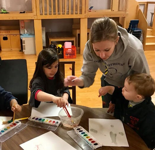 Adult and two children painting with watercolors at a table