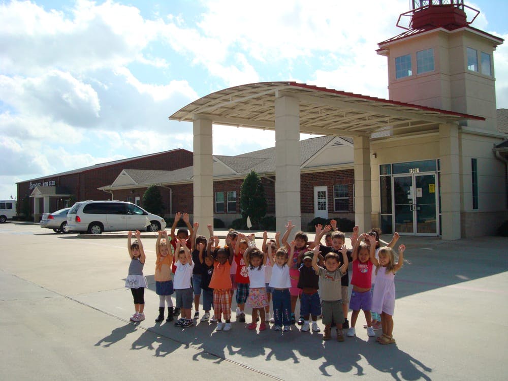 Group of children with arms raised in front of a building