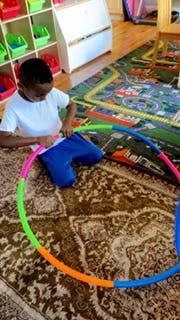 Child playing with a colorful hoop on a rug