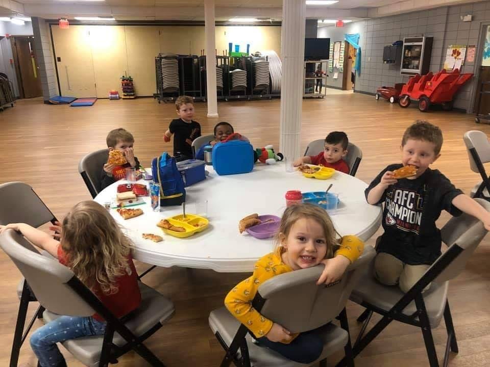 Children eating at a round table in a large room