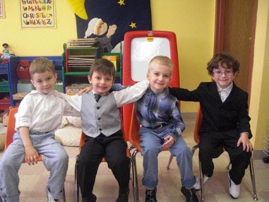Four children sitting in chairs with arms around each other