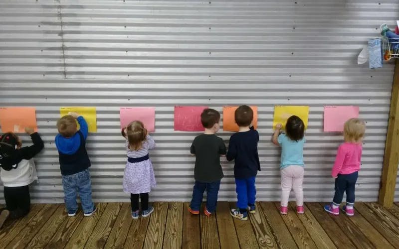 Children placing colorful papers on a wall