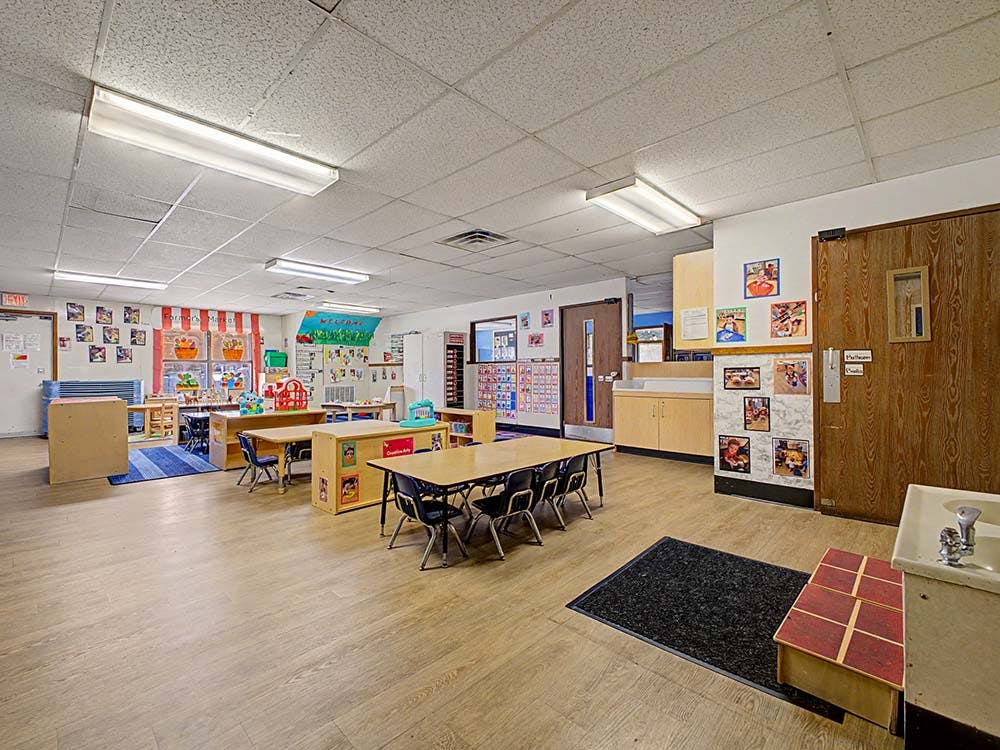 An empty classroom with tables, chairs, and colorful decorations