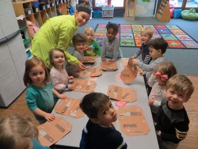 Adult and multiple children gathered around a table with crafts